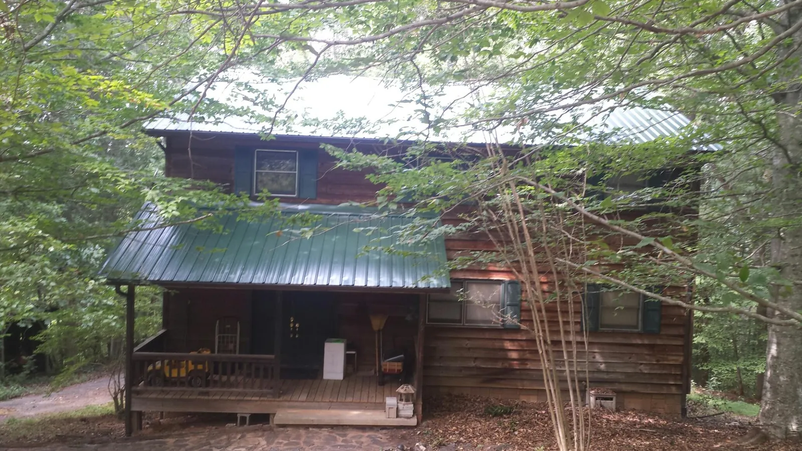 Green metal roof and covered porch on a log cabin in Manville