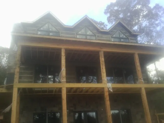 Dormers and porch framing on a large log home under construction — Roof Coating work by our crew in Manville