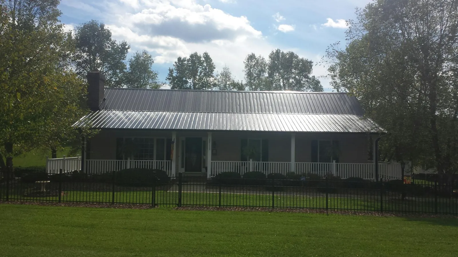Gray metal roof on a brick ranch with a full width front porch — Gutter Guard Installation work by our crew in Manville