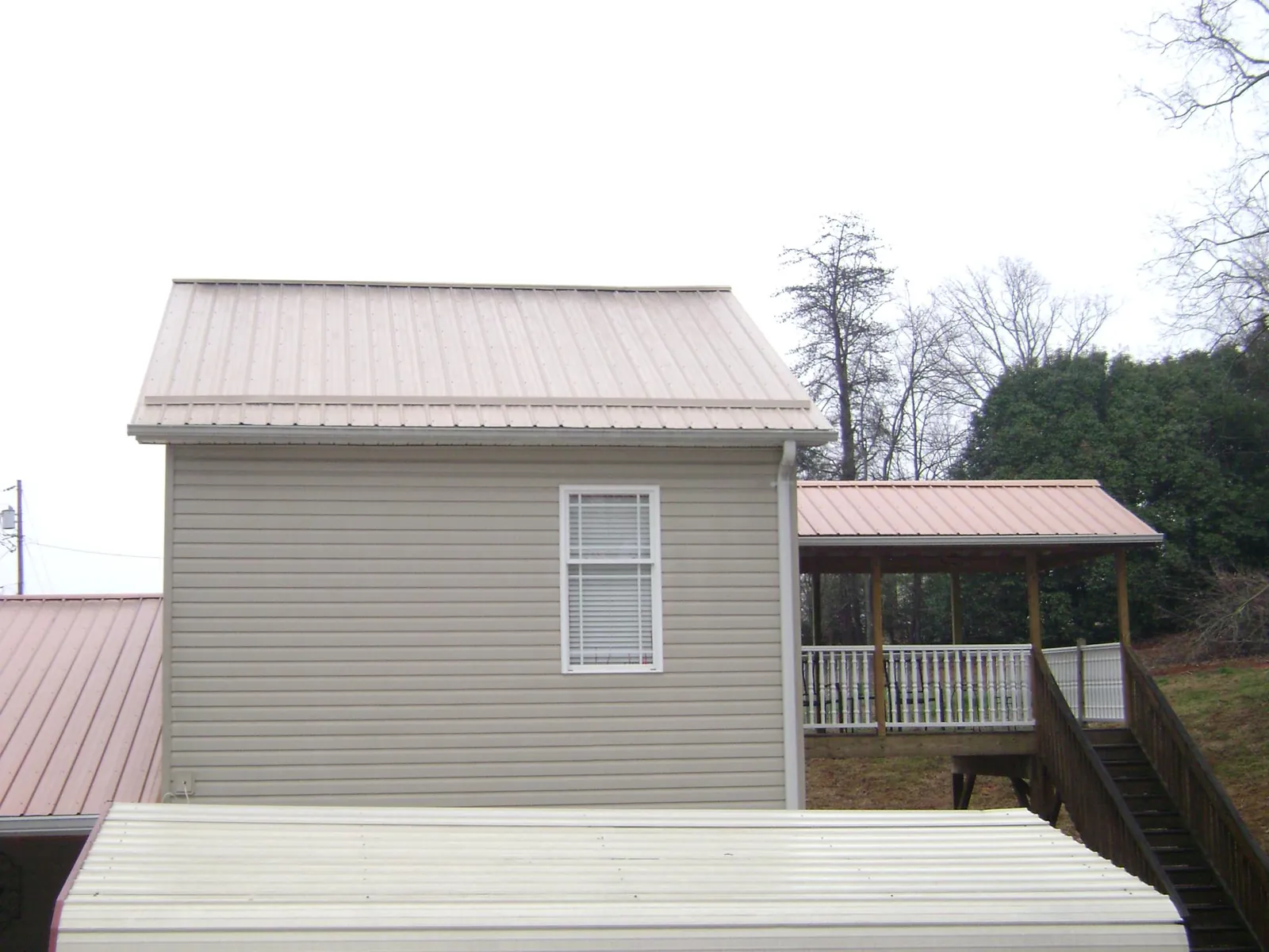 Tan metal roofs on a two story addition and attached porch, from a Roof Replacement job in Manville